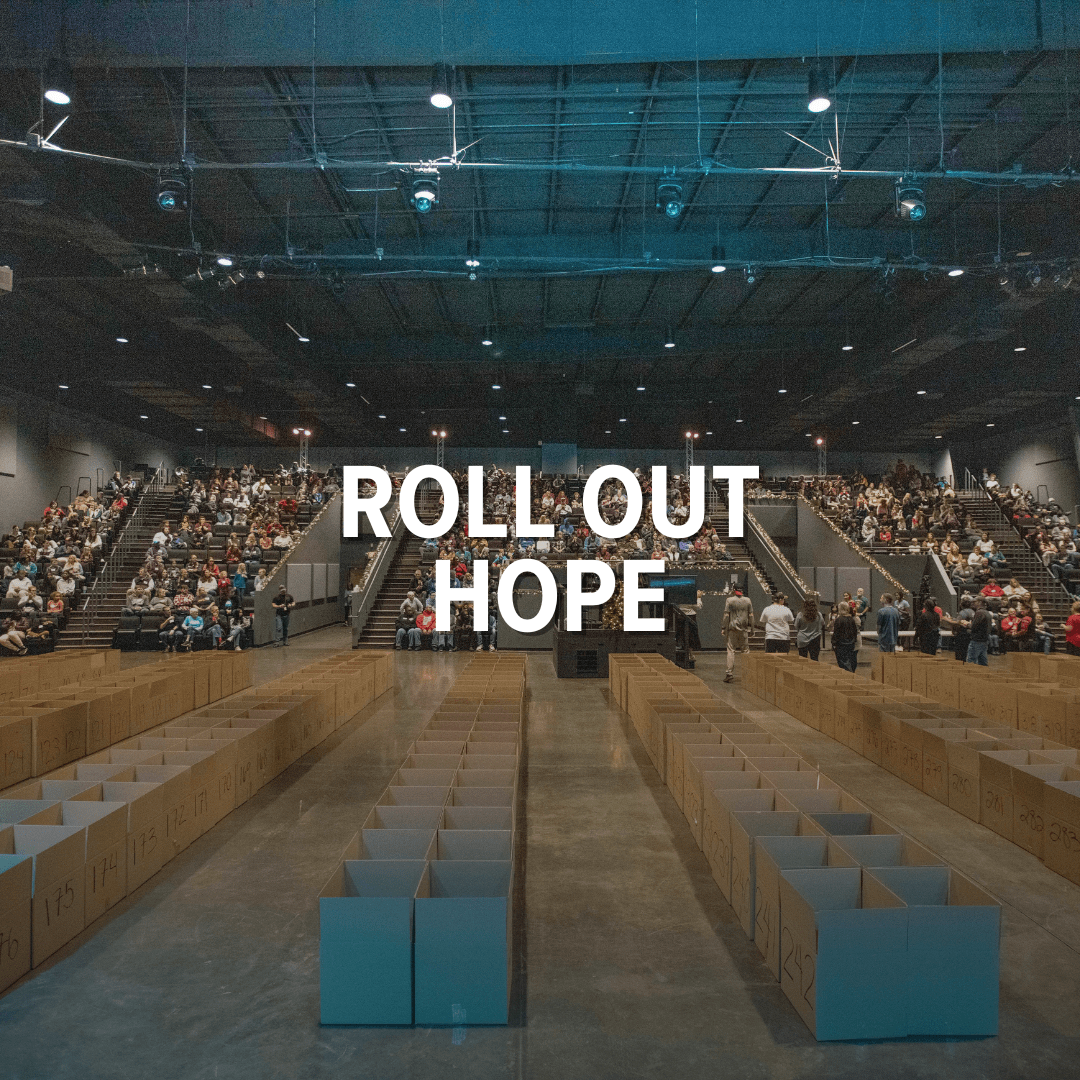 3 Crowd in large room with rows of packed aid boxes